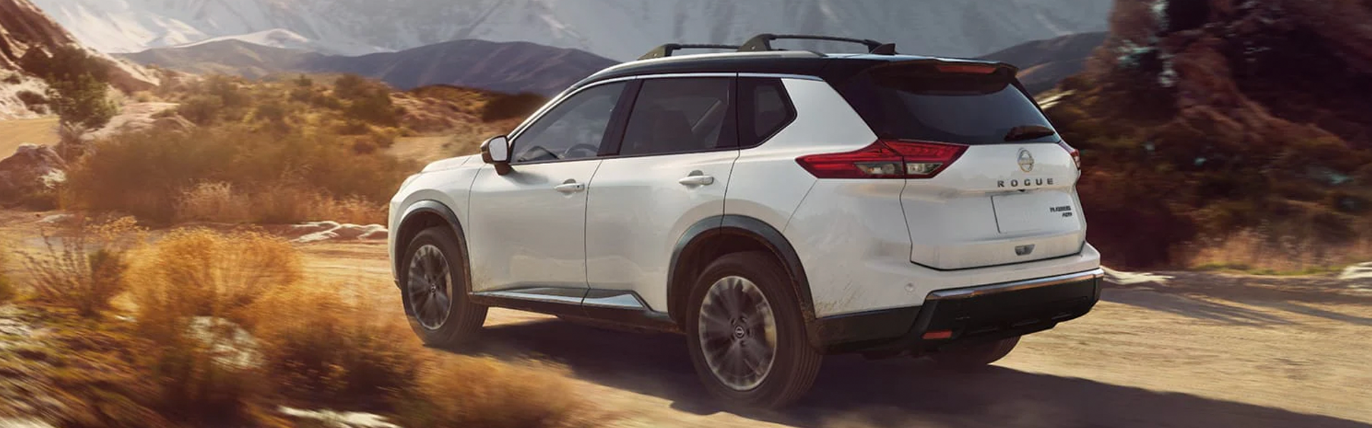 White Nissan Rogue SUV on a mountain road.